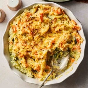 A large bowl of Bubble and Squeak, with a spoon in and a portion missing.