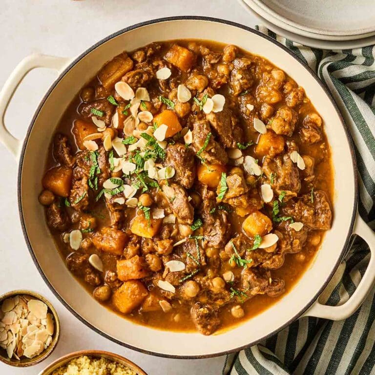 A large casserole dish filled with homemade lamb tagging, with flakes almonds on top.