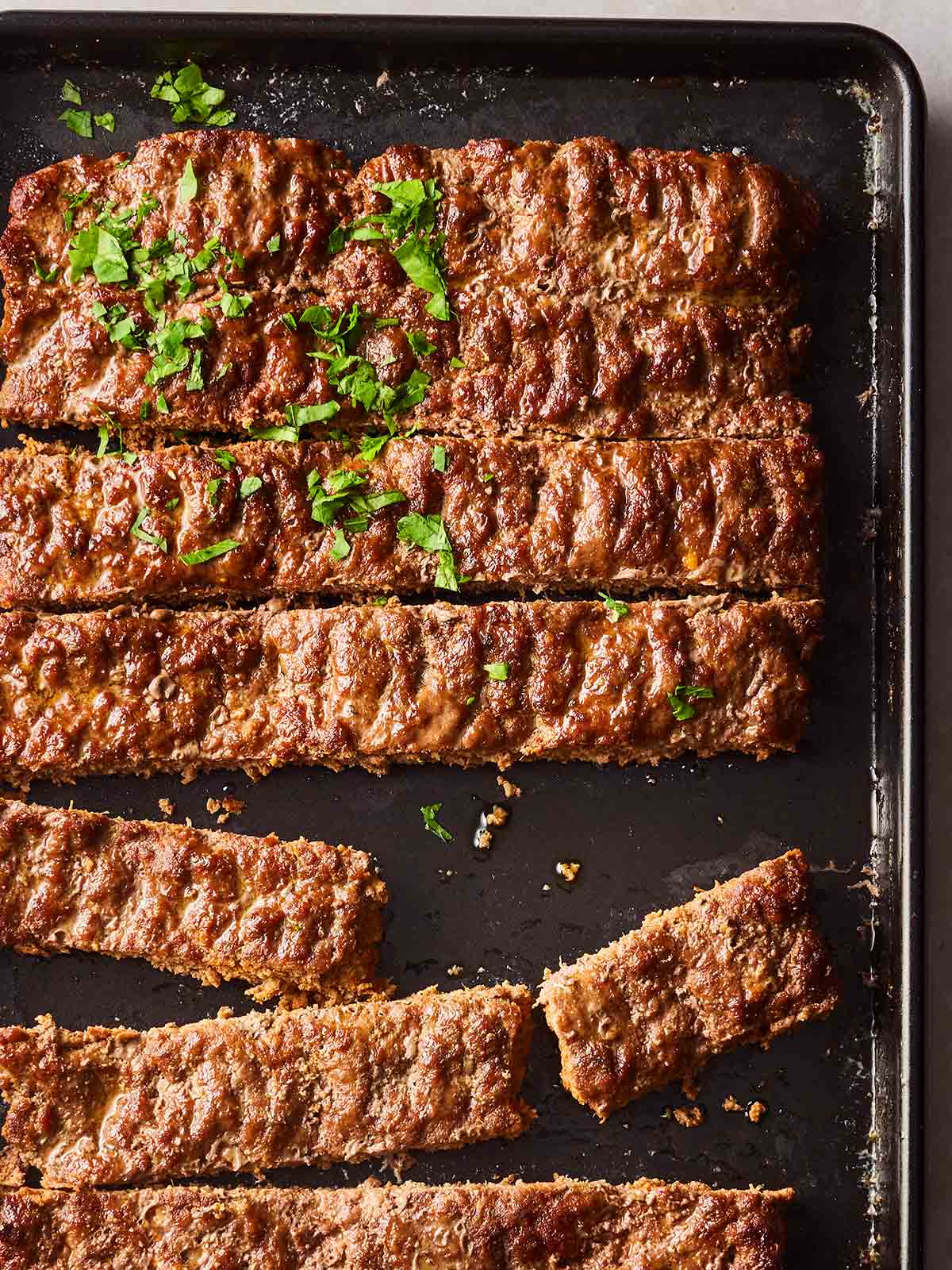 An oven tray with a cooked sheet pan kebab, beef mince in rows, ready to serve.