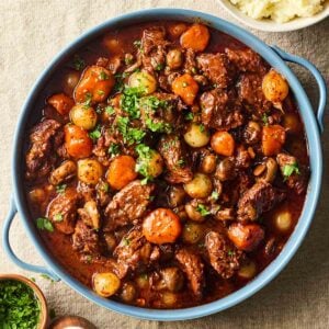 A large pot of homemade Beef Bourguignon, on a table, ready to serve with mashed potatoes.