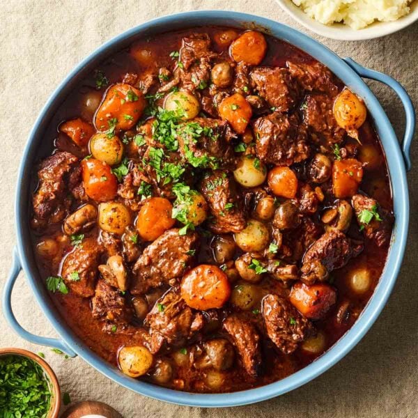 A large pot of homemade Beef Bourguignon, on a table, ready to serve with mashed potatoes.