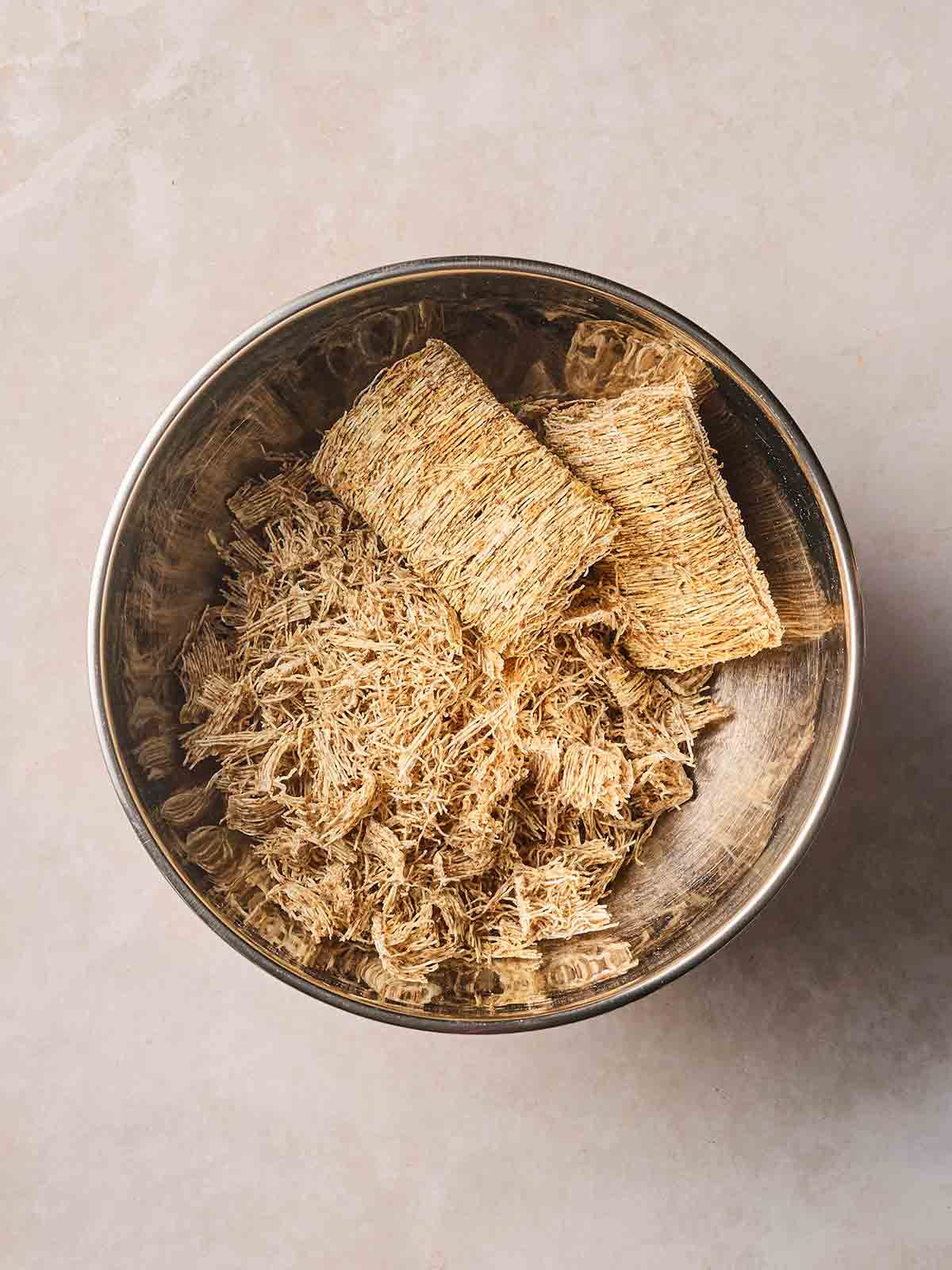 Shredded wheat slightly broken up in a bowl.