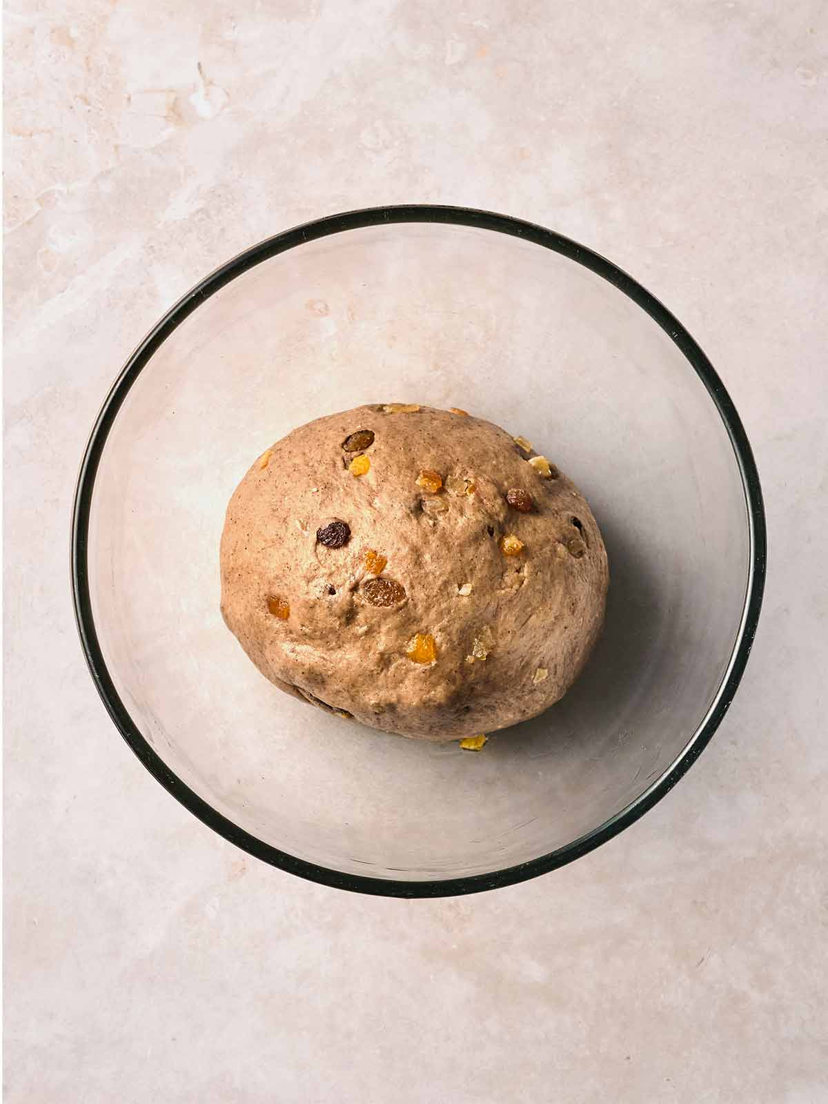 A glass bowl with homemade Hot Cross bun dough inside, being left to rise.