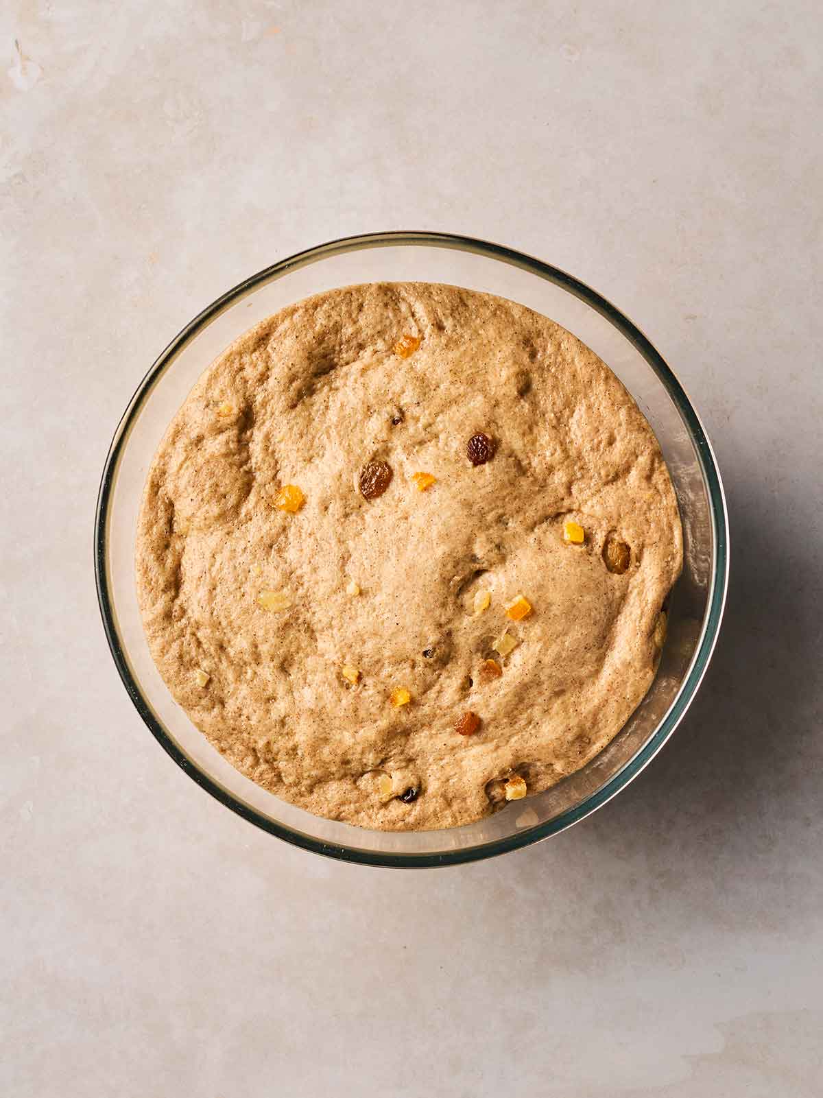 A glass bowl with risen Hot Cross Bun dough inside.