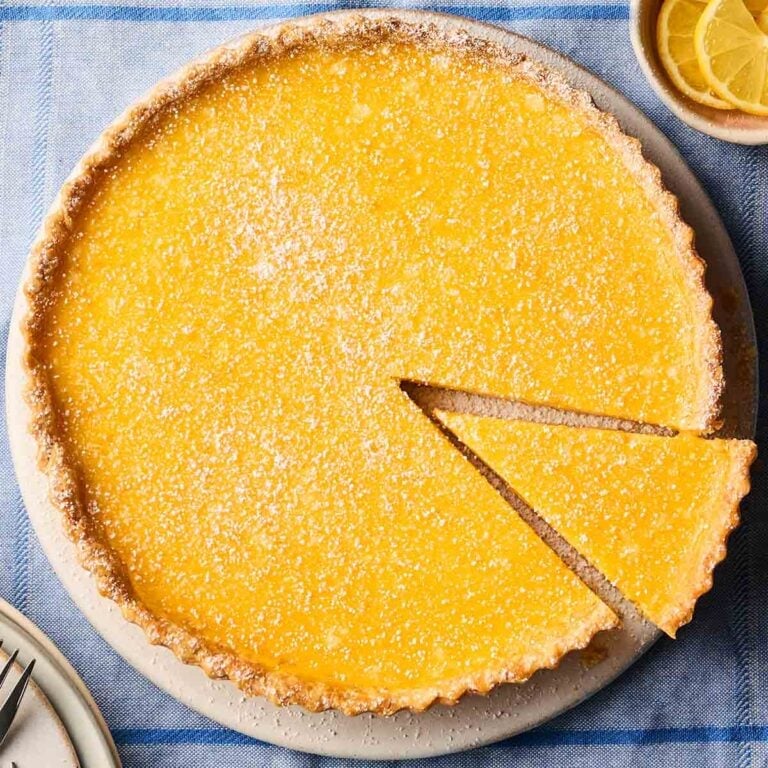 Cut out a slice of a lemon tart, ready to serve, on a table.