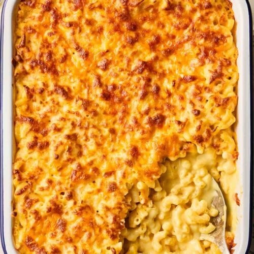A cheesy classic Macaroni Cheese dish just out of the oven, ready to serve, with a portion missing.