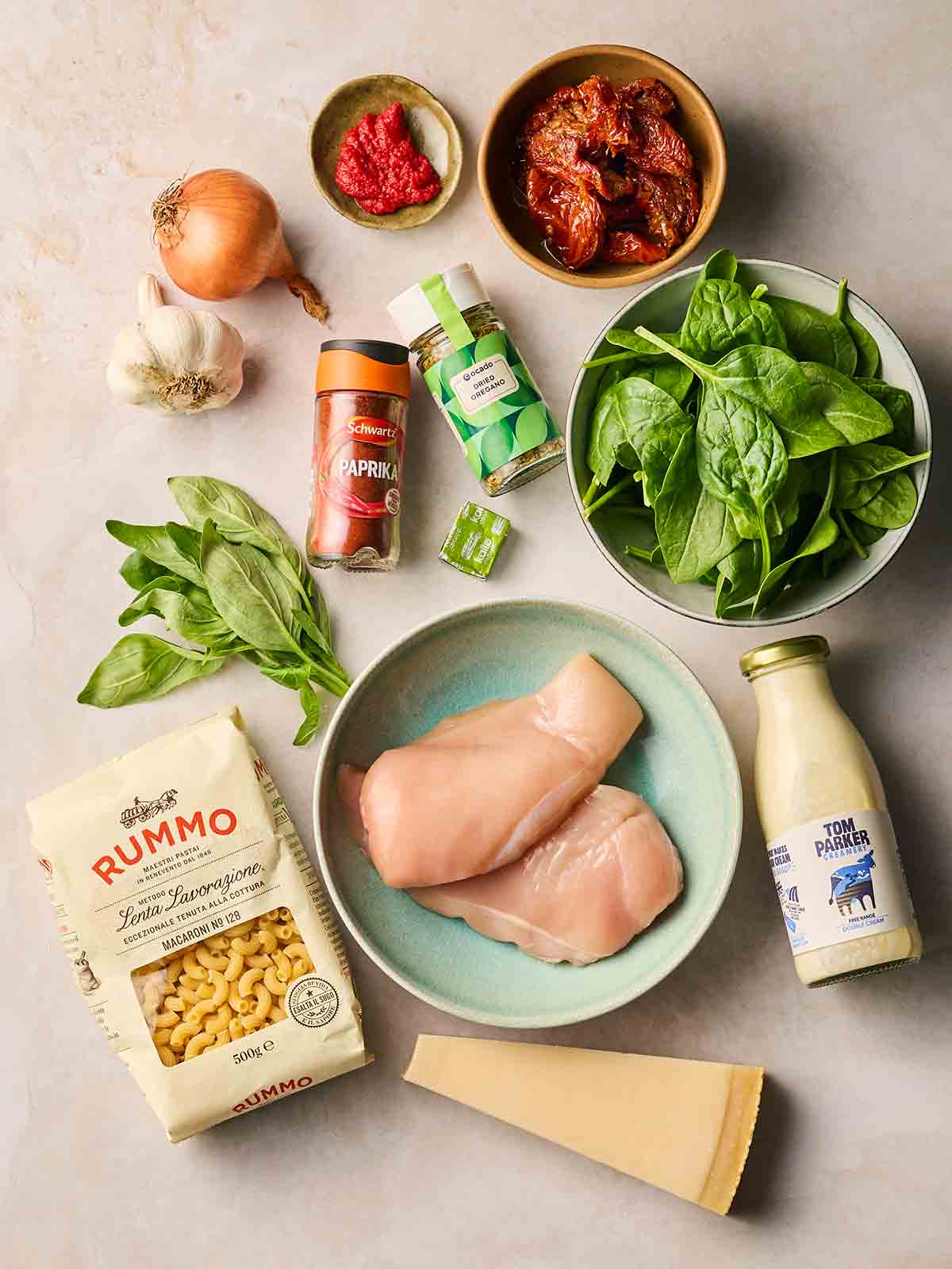 Raw ingredients for making Marry Me Chicken Soup on a white surface.