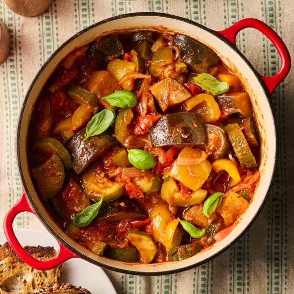 A classic French style stew, Ratatouille, in a big pan on a table, ready to serve with crusty bread at the side.