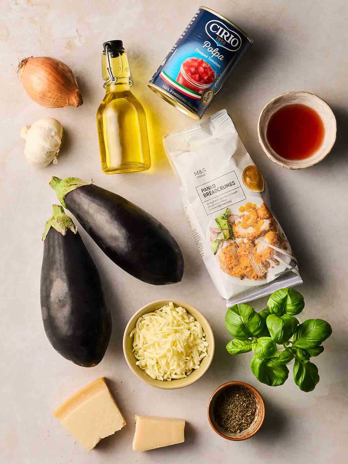 The individual ingredients for making Aubergine Parmigiana laid out on a white surface.
