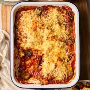 A baked Aubergine Parmigiana with a portion missing on a table, ready to serve the rest.