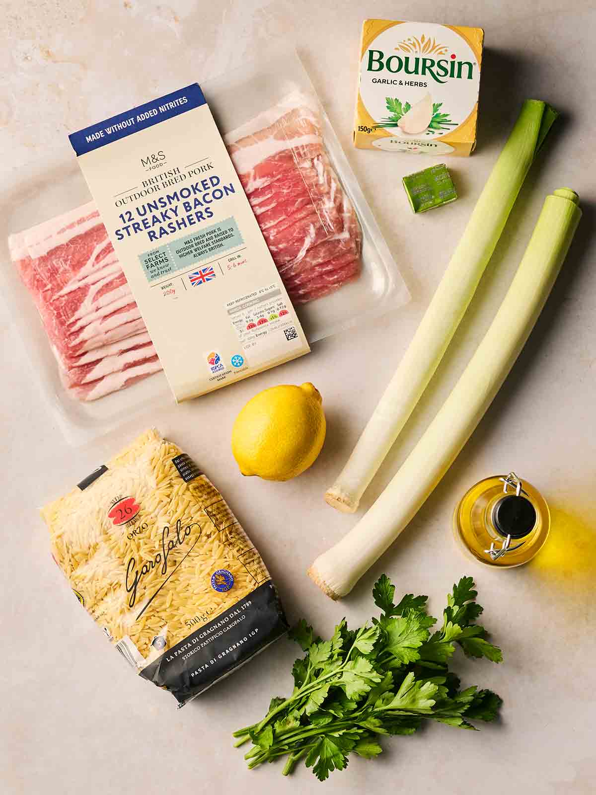 Ingredients for making Bacon and Leek Orzo laid out on a white counter top.