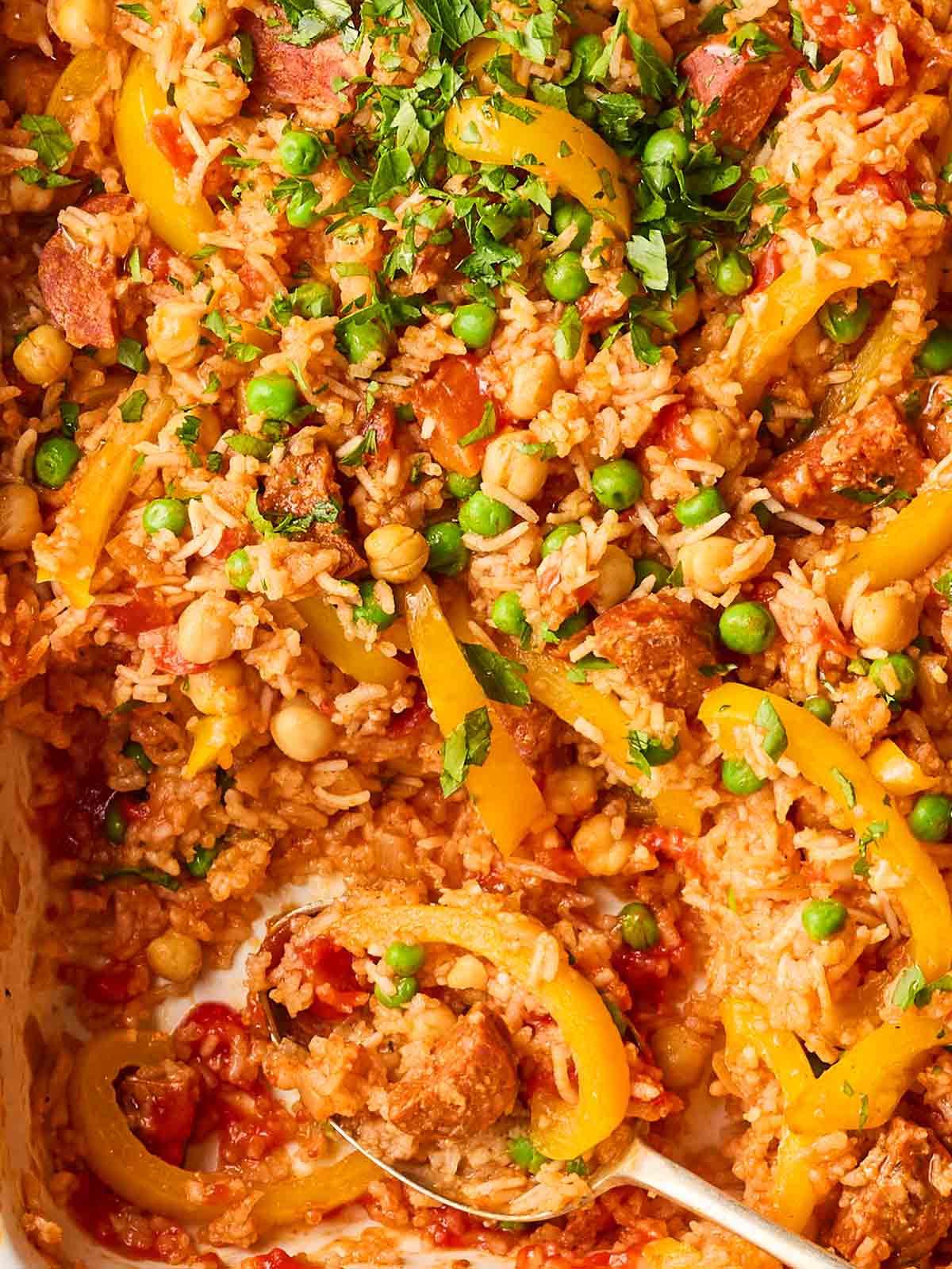 A close up of baked rice with chorizo, peppers, chickpeas and peppers.
