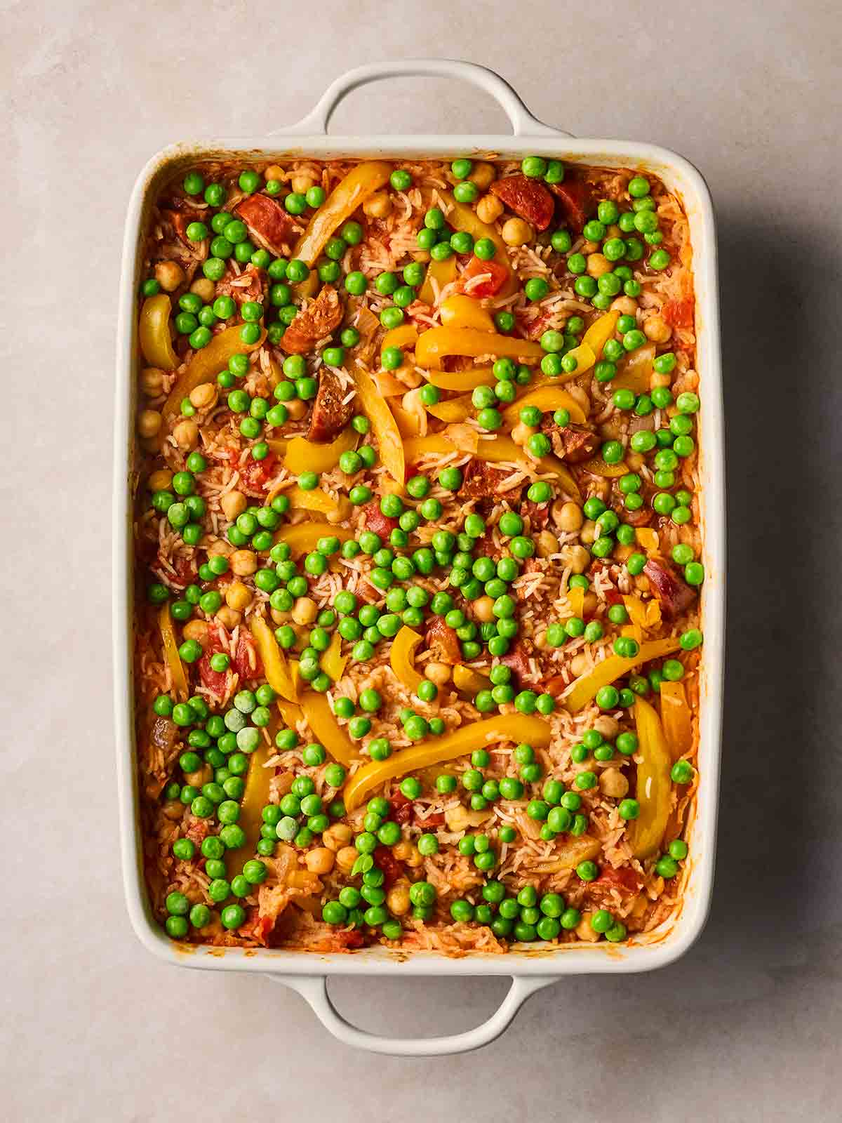 Frozen peas on top of a baked Chorizo and Rice dish, ready to go back in the oven to cook.