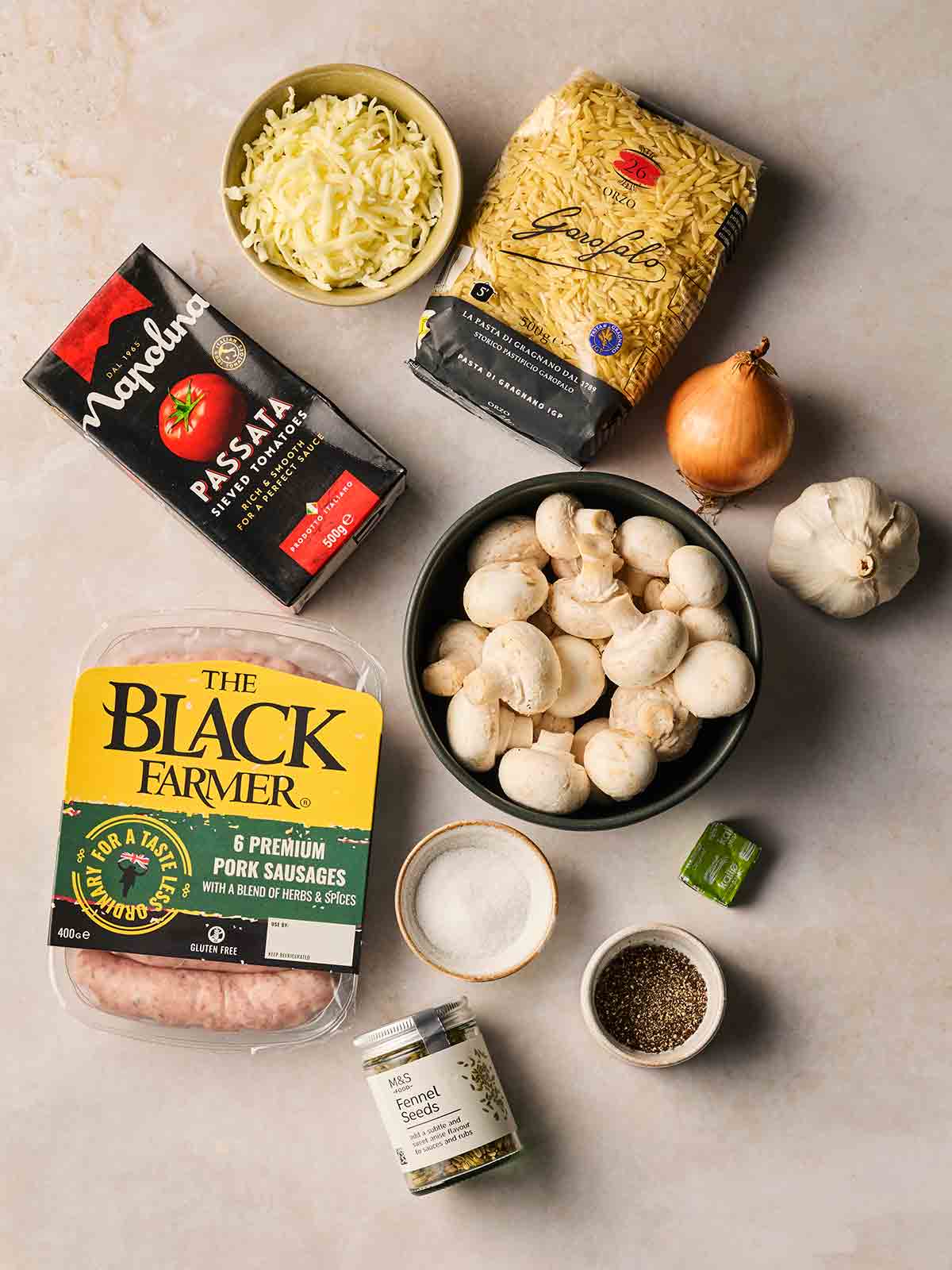 Ingredients for making a Sausage Orzo Bake recipe laid out on a white counter.