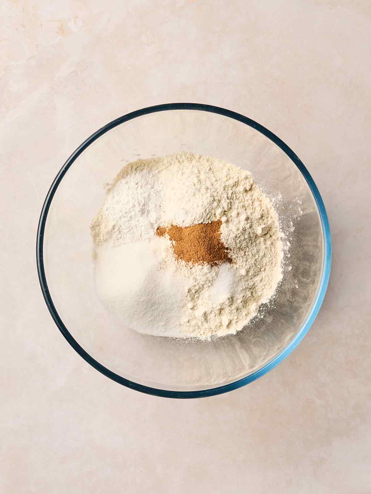 A glass bowl with dry ingredients for making Banana Pancakes, ready to mix.