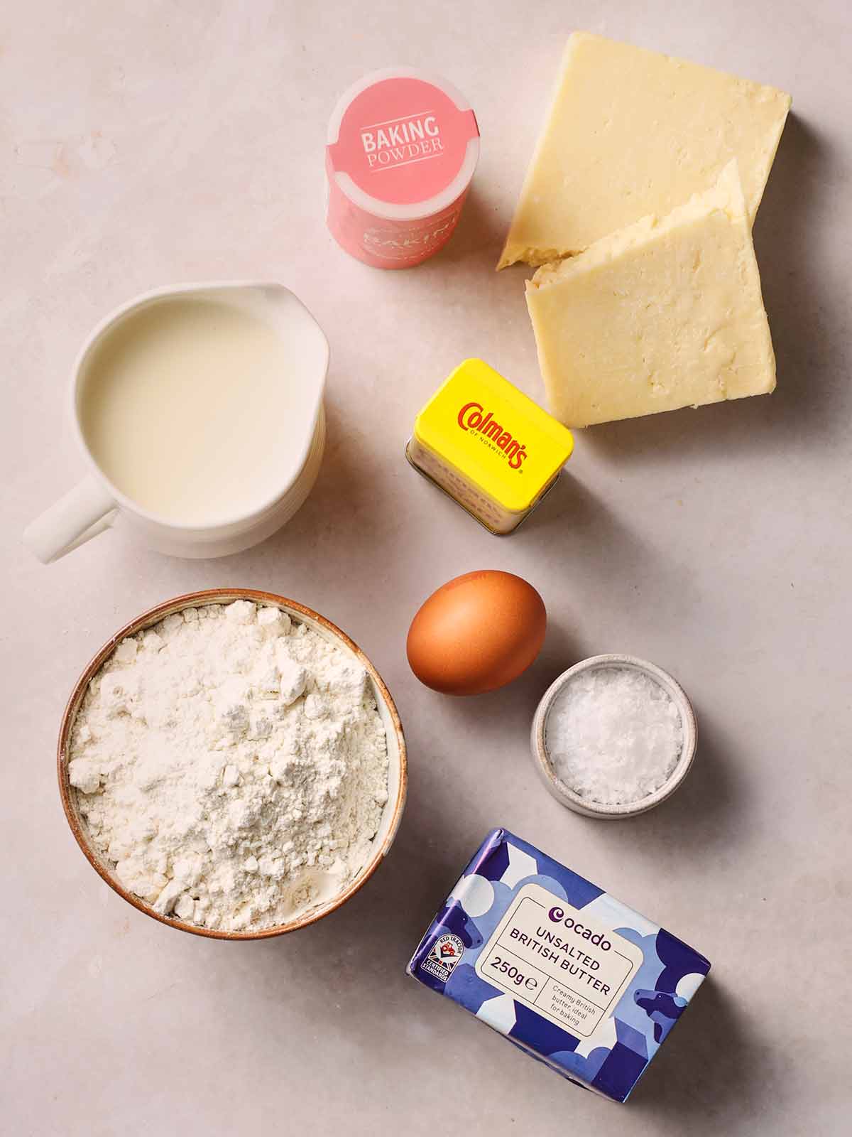 The ingredients for making Cheese Scones laid out on a white surface from above.