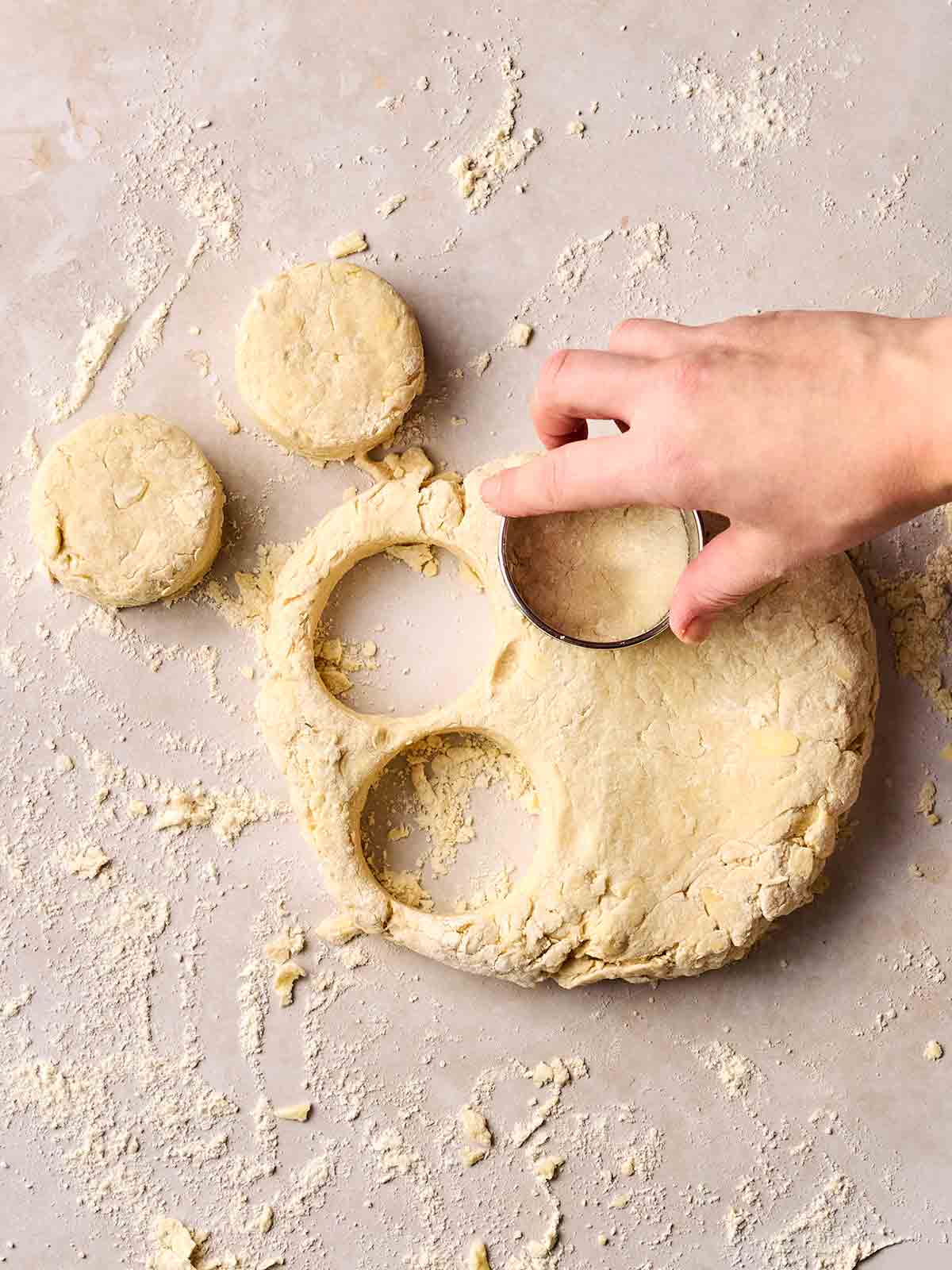 A hand using a cutter on a floury dough for making Cheese Scones.