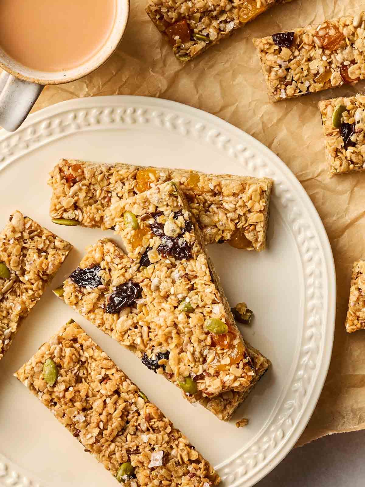 A plate with some homemade breakfast granola bars on, with more at the side and a cup of tea.