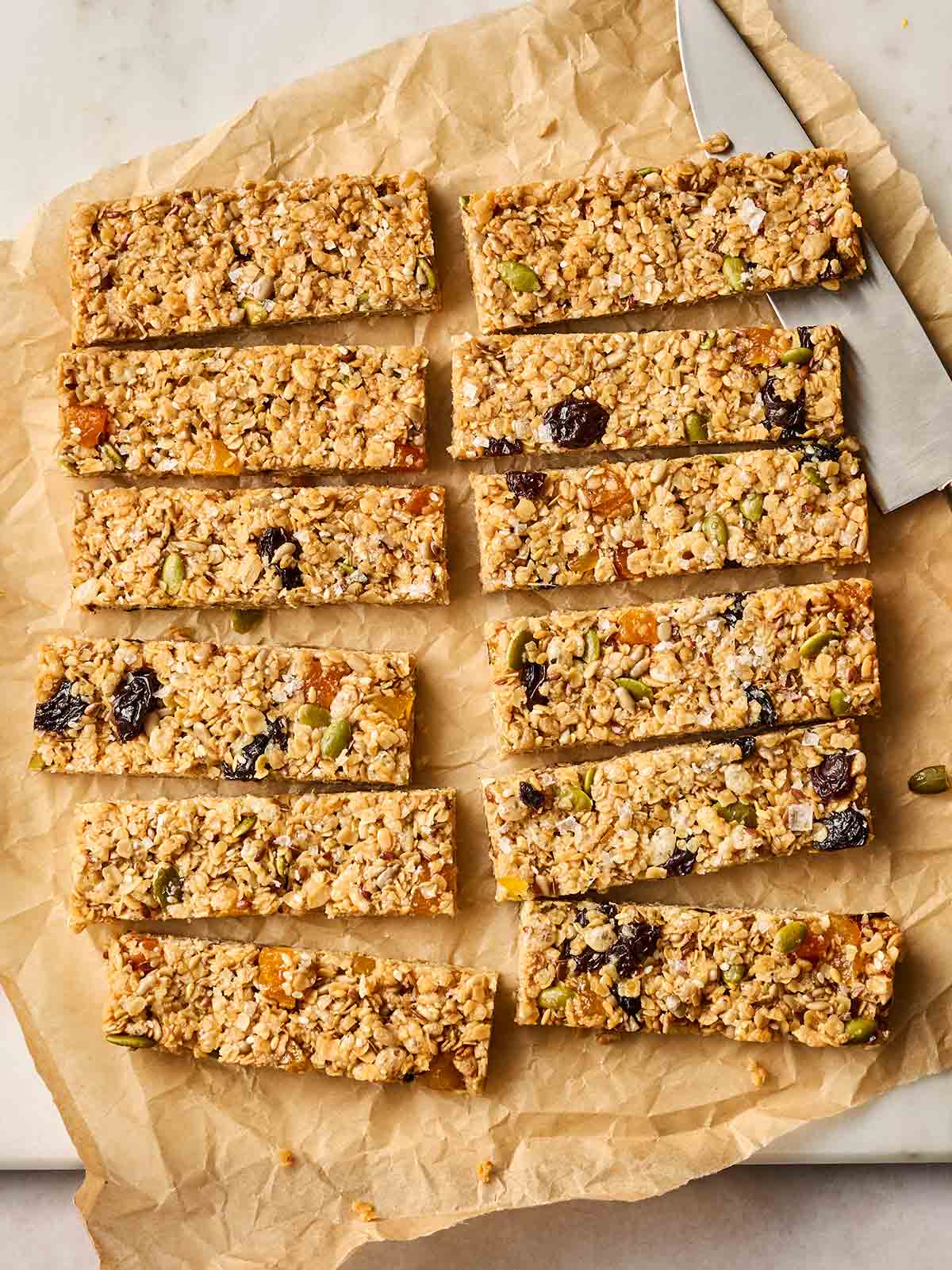 A batch of granola bars cut up on top of baking paper, ready to eat.