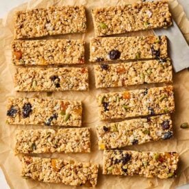 A bath of 12 cut granola bars on a baking paper sheet.