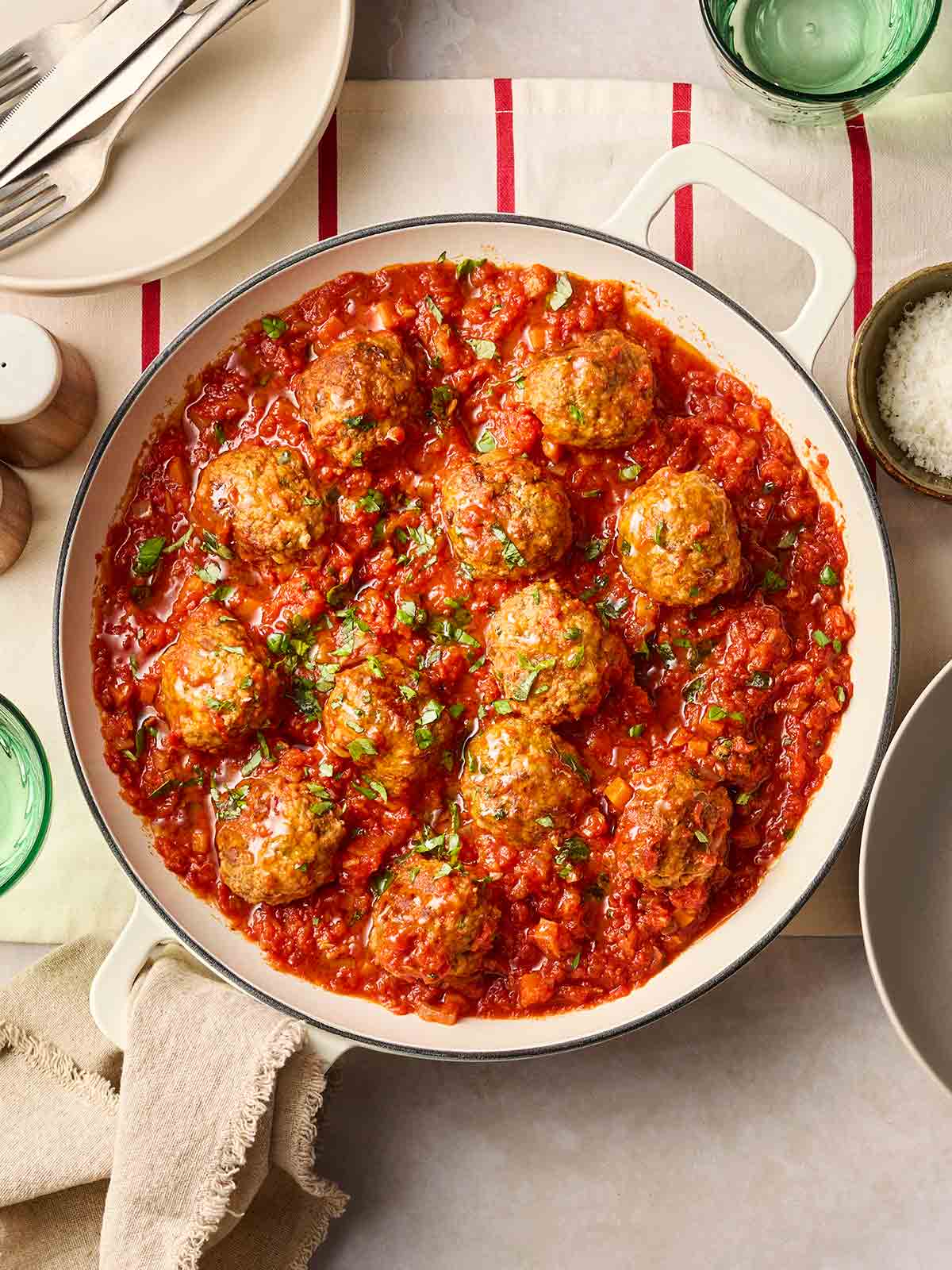 A pan filled with a rich Italian-style meatballs in a sauce, on a table ready to serve.