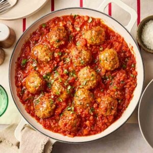 Classic meatballs in a tomato sauce, in a white pan on a set table.