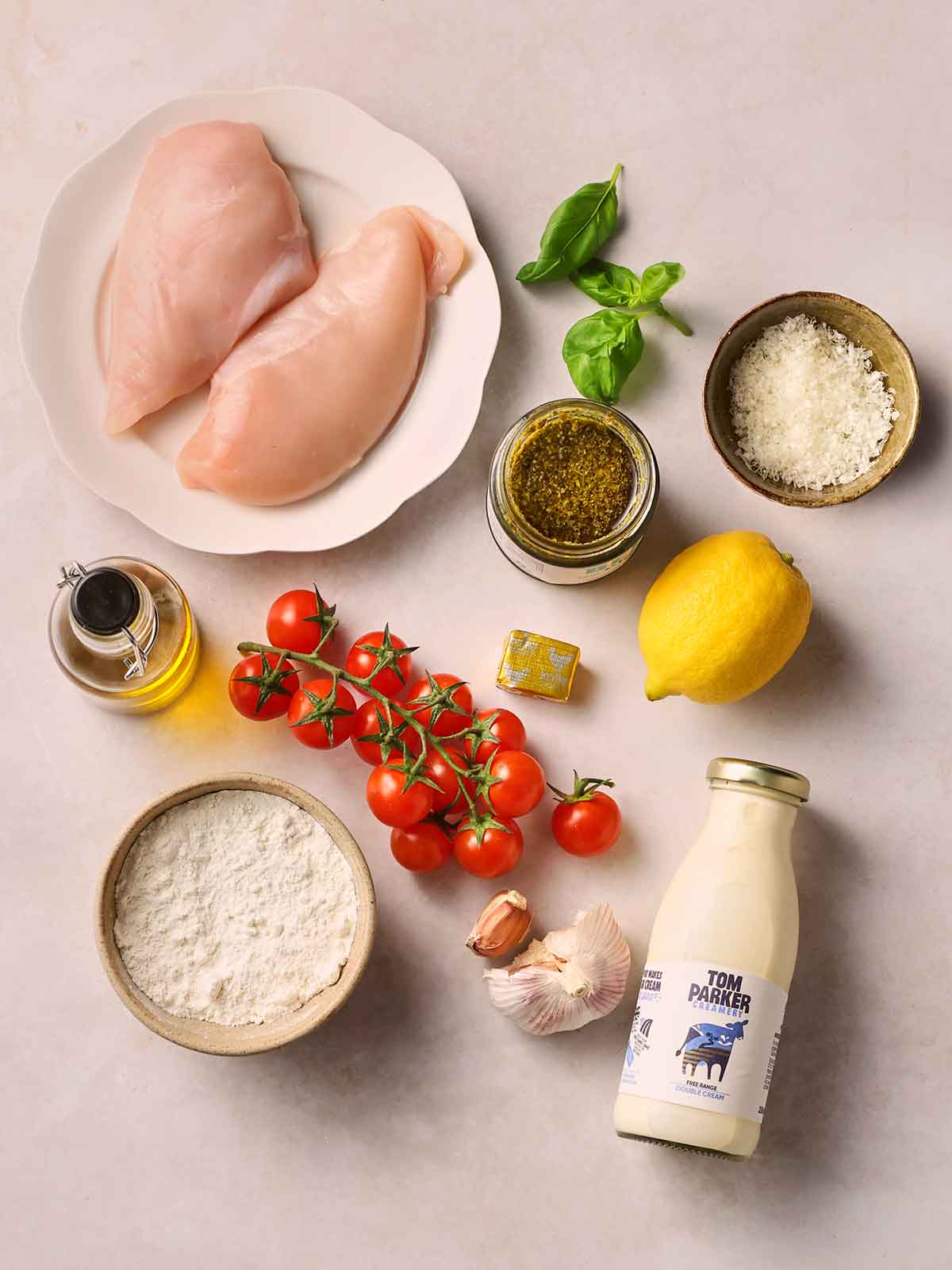 A white counter top filled with ingredients to make Pesto Chicken for dinner.