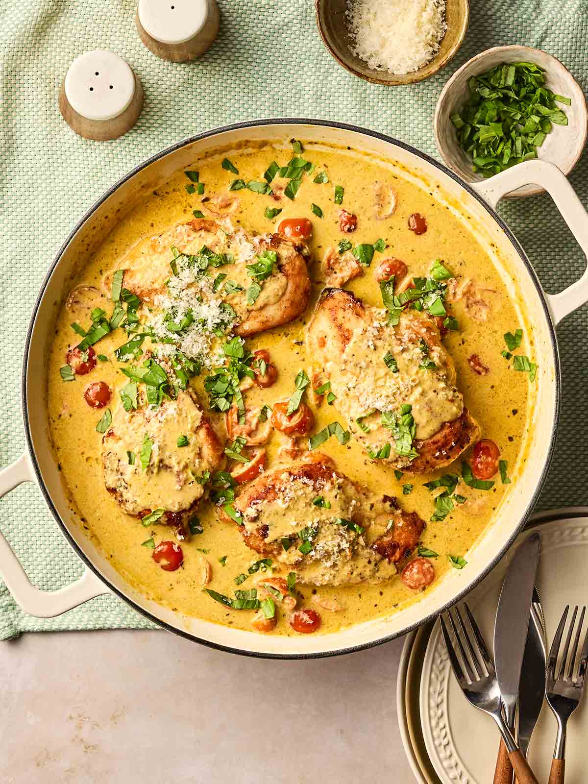 A large pan of creamy Pesto Chicken on a set dining table.