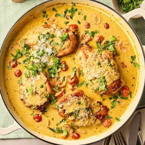 A pan of pesto chicken with tomatoes, creamy sauce and basil.