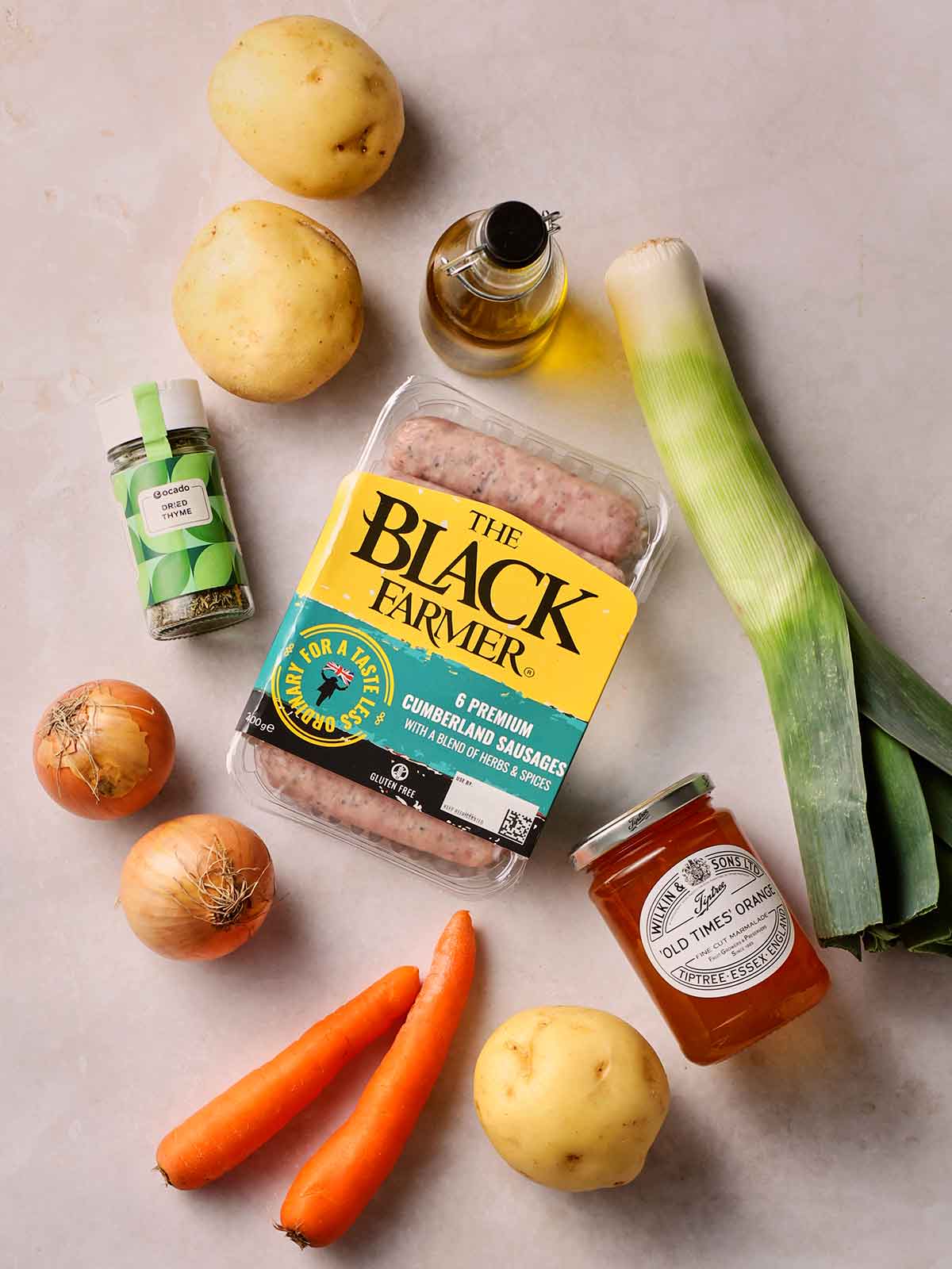 The ingredients for making a Sausage Tray Bake laid out on a white counter top.