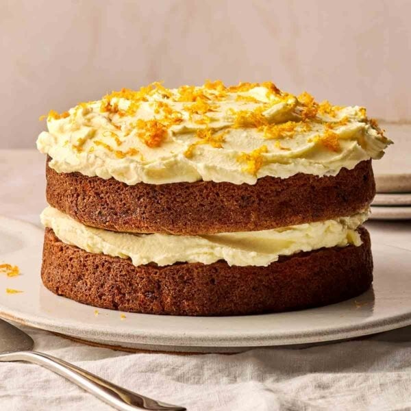 A side view of a homemade Carrot Cake, with two tiers and icing in the middle and on top.