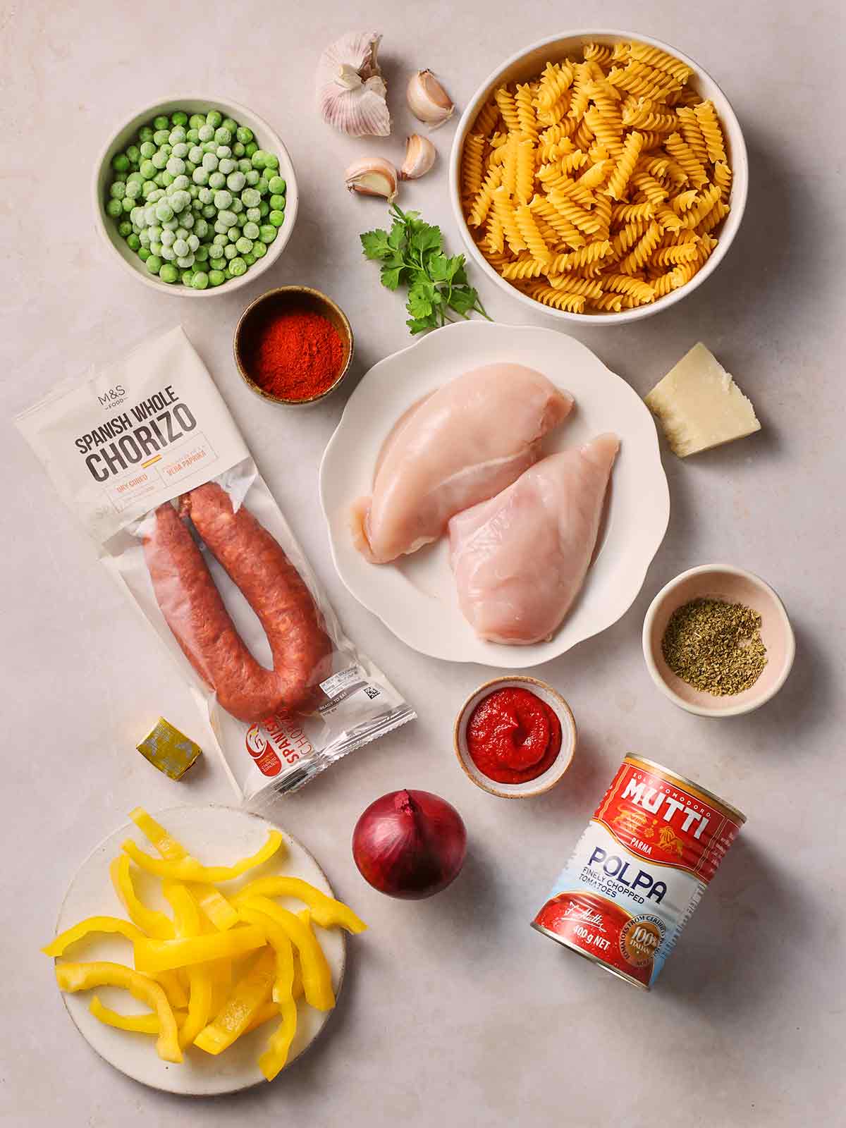 The ingredients for making Chicken and Chorizo Pasta laid out on a white counter.