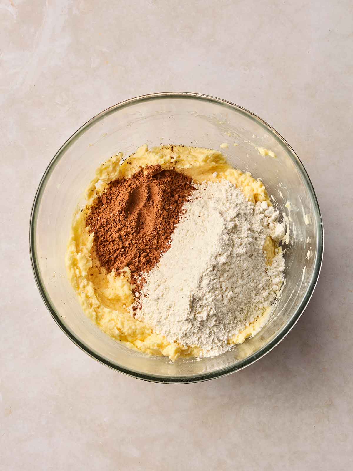 A glass bowl with chocolate bake batter ingredients inside, ready to mix.