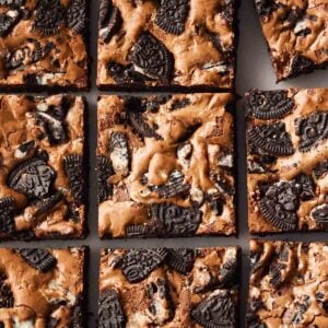 Squares of homemade baked Oreo Brownies on a white surface.