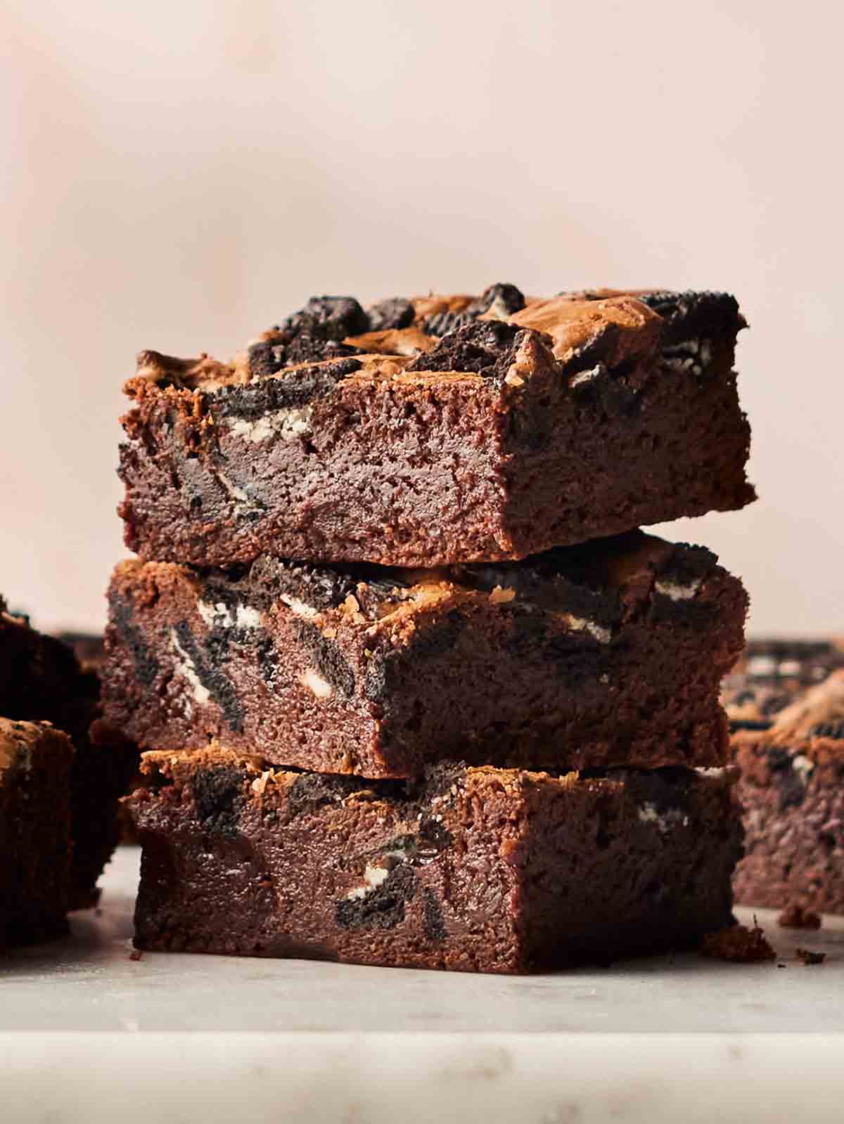 A side angle of three stacked Oreo Brownies, showing their gooey filling.