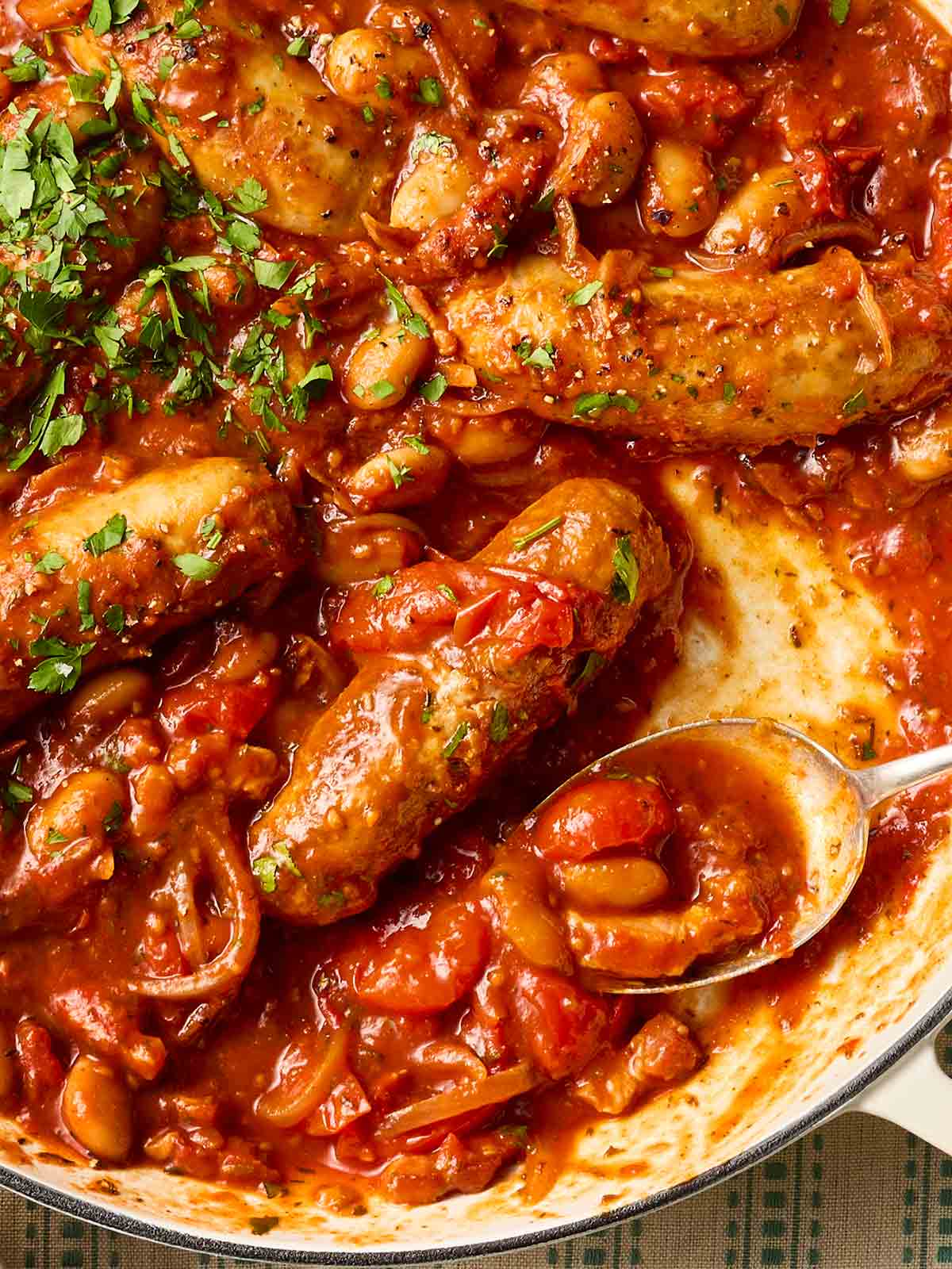 A close up of a pan of sausage casserole being served with a spoon.