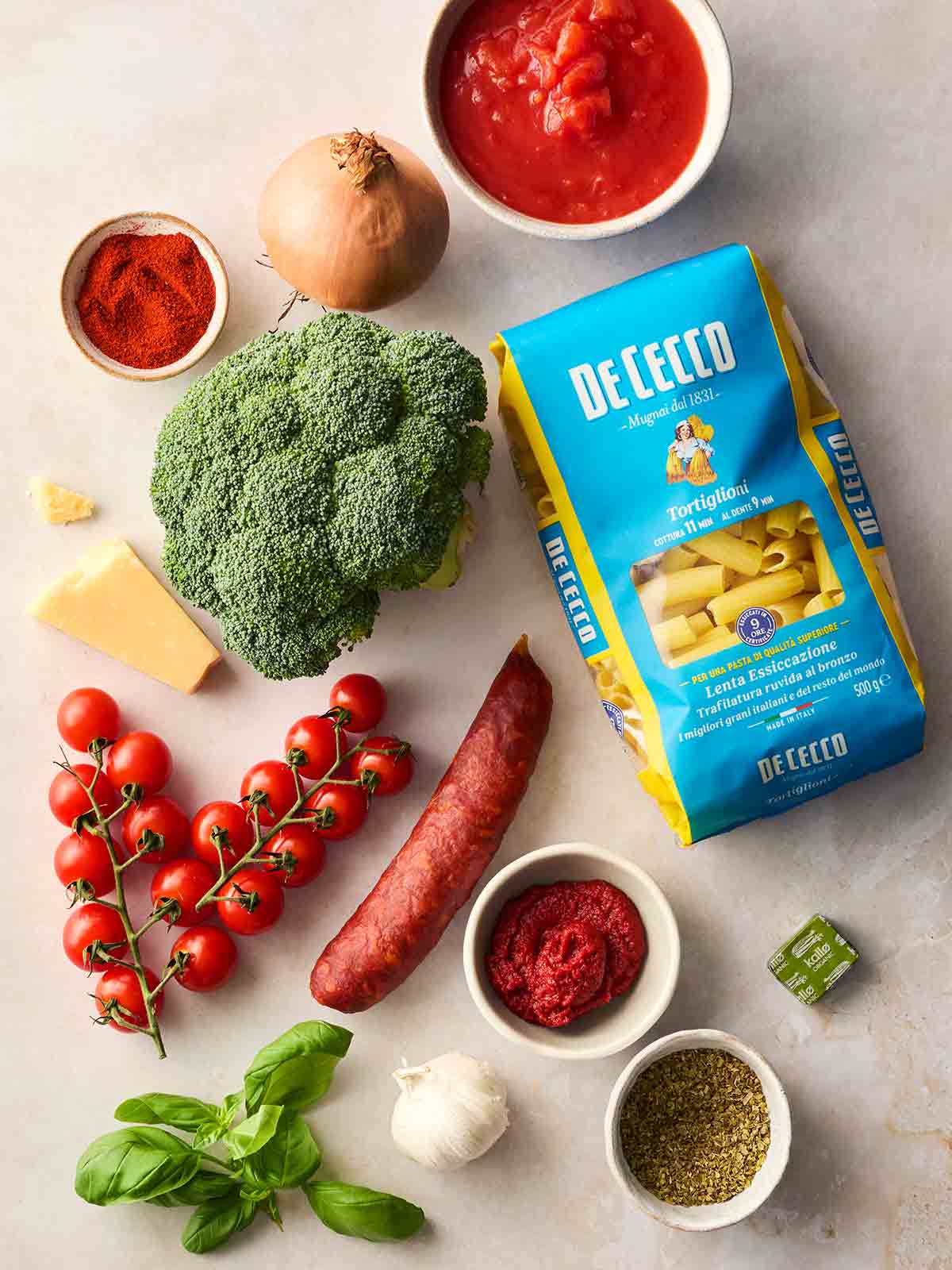 The raw ingredients for making Chorizo Pasta laid out on a white surface.