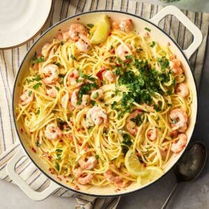A pan of cooked prawn linguine in the middle of a table, ready to be dished up onto plates.