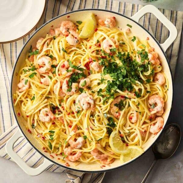 A pan of cooked prawn linguine in the middle of a table, ready to be dished up onto plates.