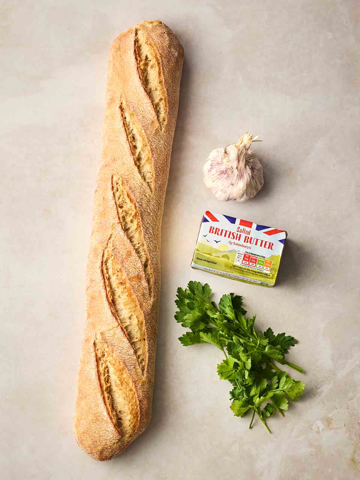 The ingredients for making Homemade Garlic Bread laid out on a white counter.