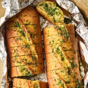 A homemade garlic bread baguette in two, inside foil it was baked in.