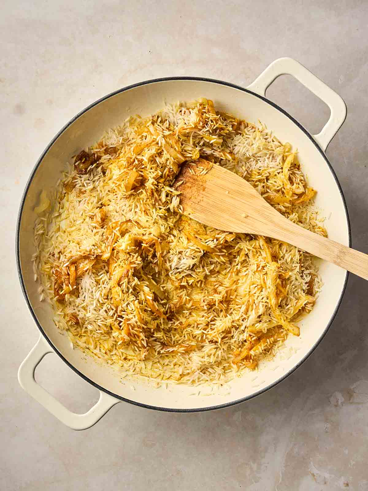 A pan of rice cooking with spices and onion.