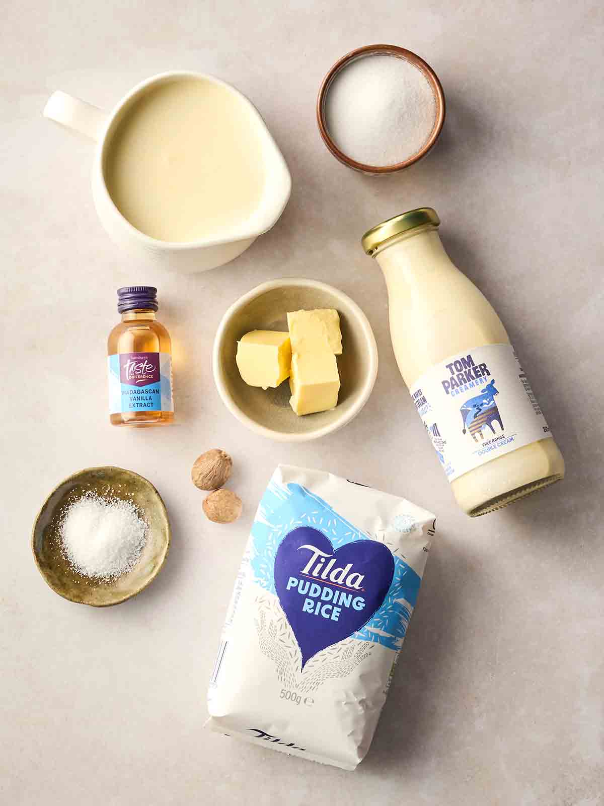 The ingredients for making a classic rice pudding laid out on a white surface.