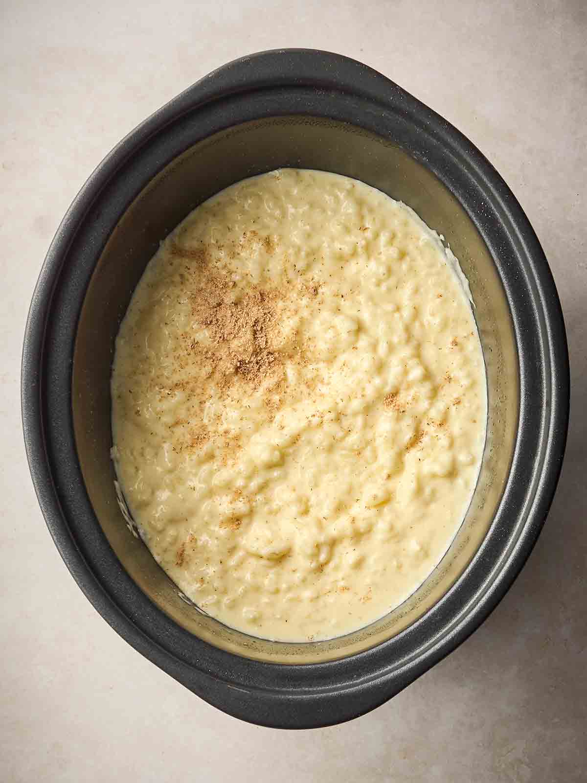 A slow cooker pan with cooked rice pudding inside.