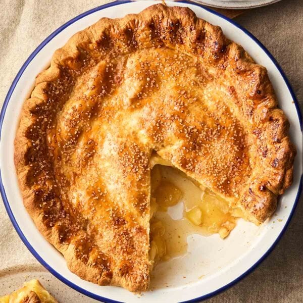A close up of a classic Apple Pie, with a slice missing, showing the juicy apple filling.