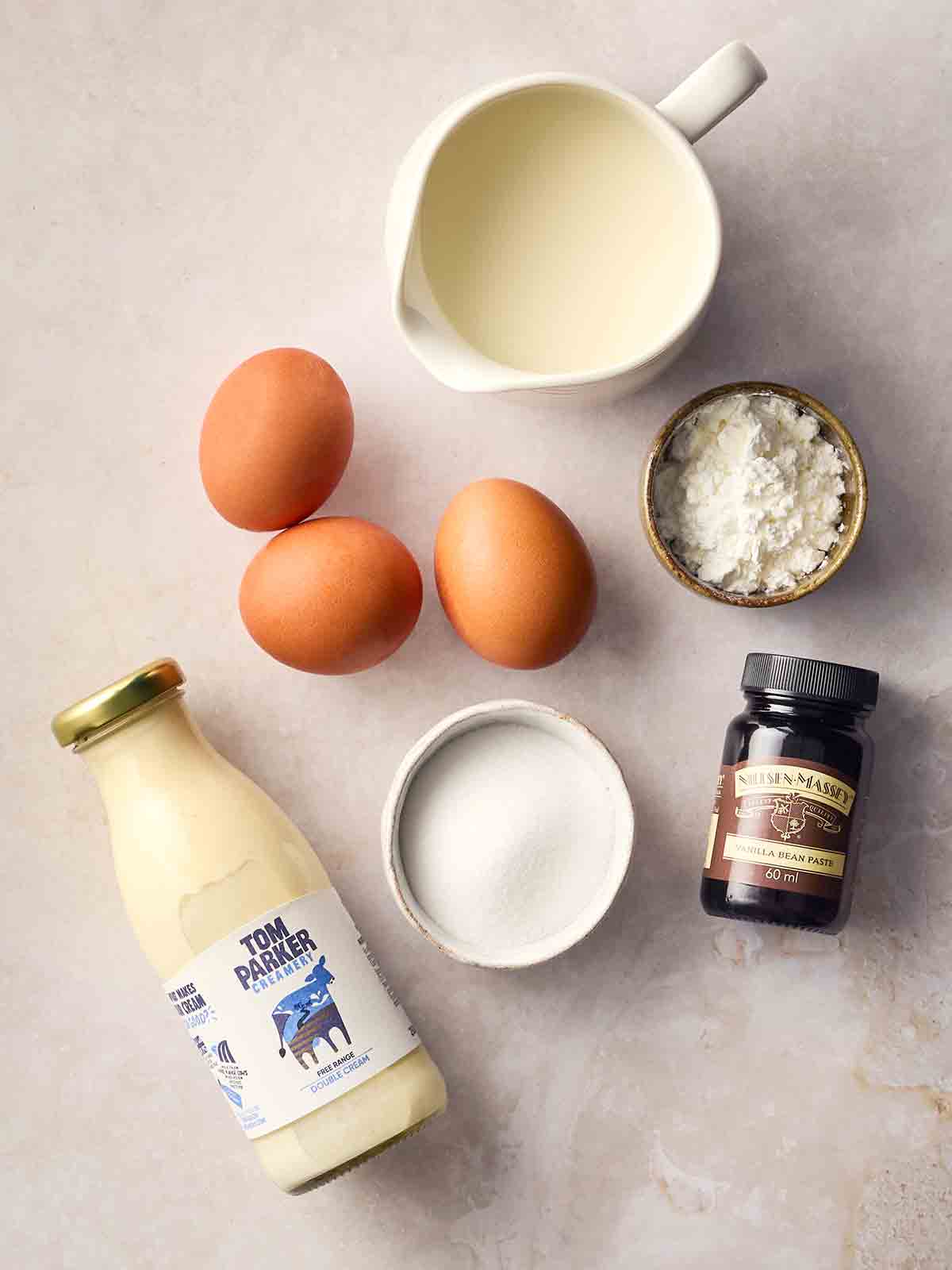 The ingredients for making a classic custard recipe laid out on a white surface.