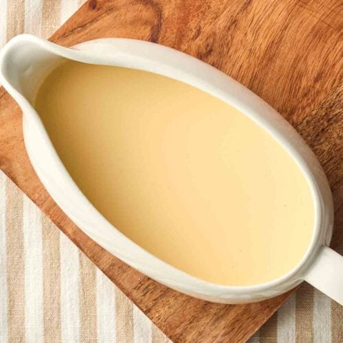 A jug of vanilla custard on a board, ready to serve.