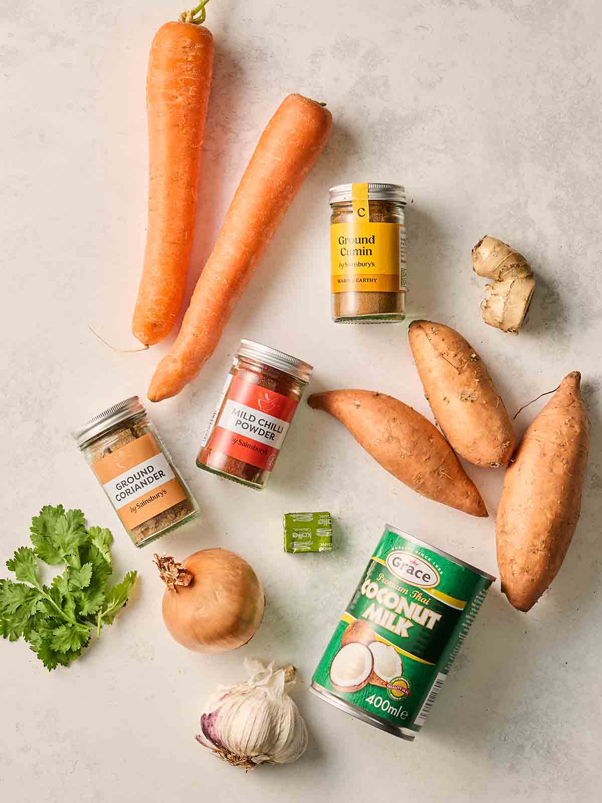 The ingredients for making sweet potato soup laid out on a white counter.